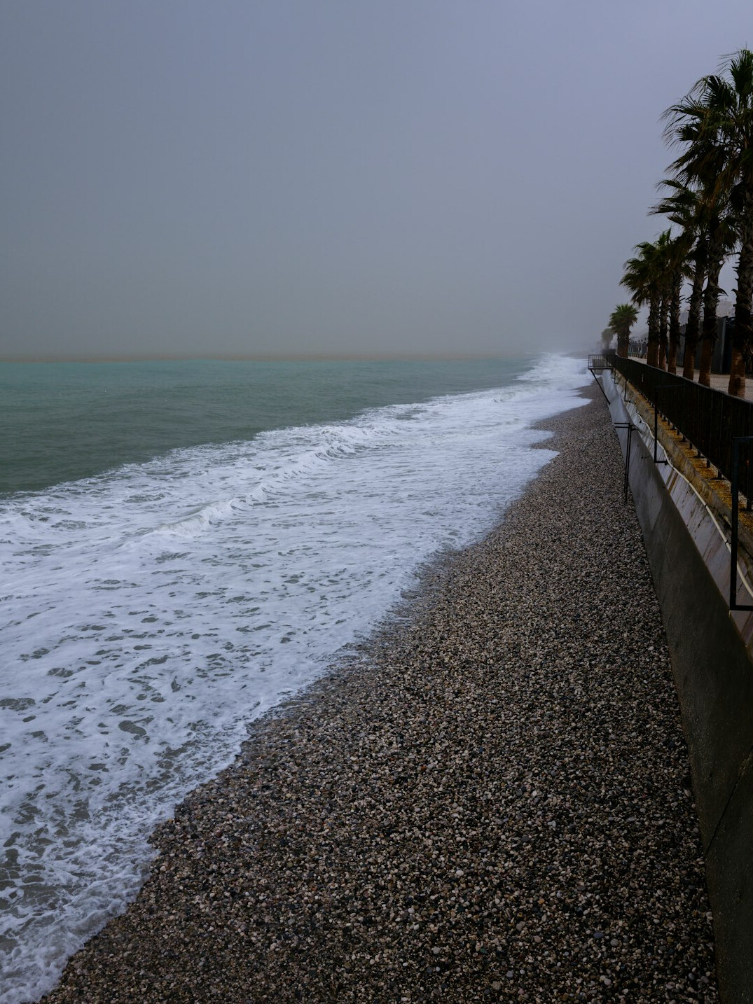 Rolling waves hitting a coastal promenade during a storm